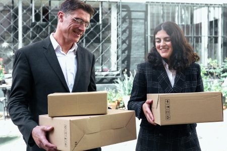 Deux collaborateurs souriants portant des colis, incarnant la logistique humaine et soignée d’Indifair.