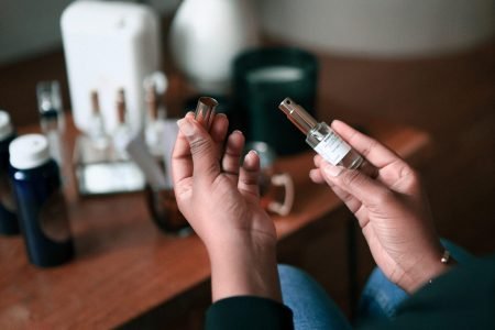 Mains féminines tenant un flacon de parfum, dans un espace sensoriel Indifair dédié aux tests et compositions olfactives.