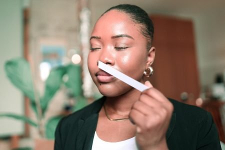 Femme testant une touche à parfum les yeux fermés, concentrée sur l’évaluation sensorielle d’une fragrance.
